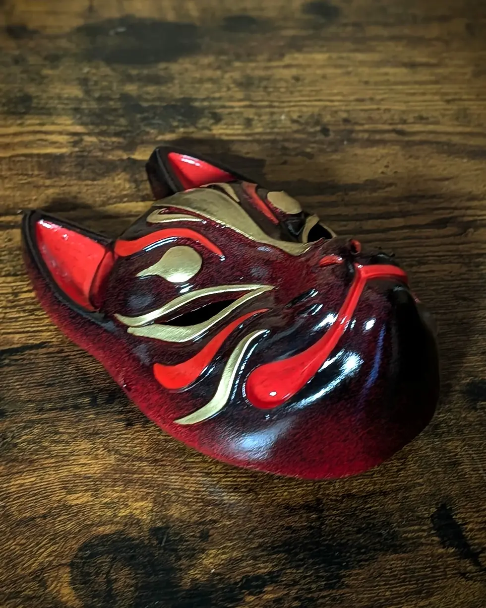 Miniature : Masque Kitsune bordeaux posé sur table en bois, finition laquée brillante, masque japonais fait main Dai Yokai