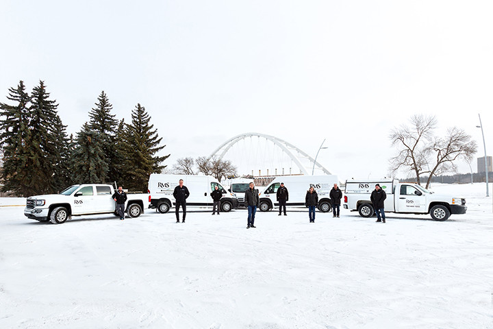 Residential Maintenance Services team standing in front of their vehicle fleet by the Walterdale Bridge in downtown Edmonton