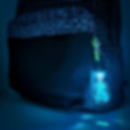 blue light up keychain of an acoustic guitar with outdoor scene hanging from a backpack