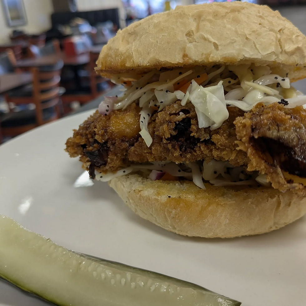 Fried chicken sandwich topped with slaw, served with a pickle spear at Black Sheep Cafe.