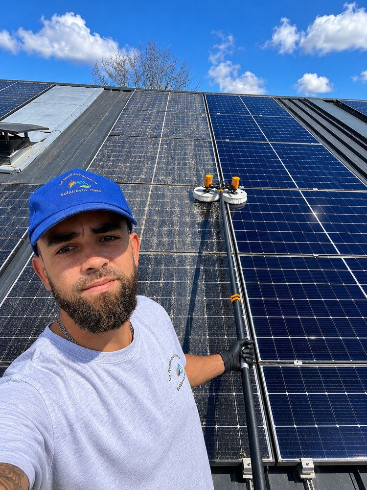 Vue rapprochée d'un technicien en train de nettoyer un panneau solaire