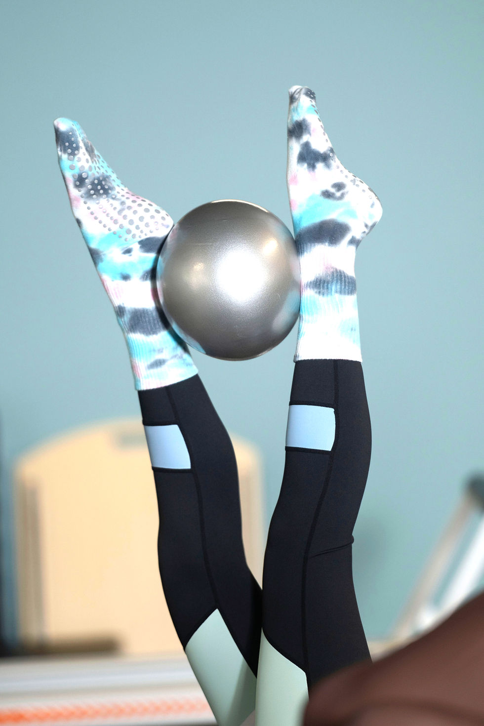Person balancing a pilates ball between feet at O2 Pilates Boutique Reformer Pilates Saxonwold Johannesburg