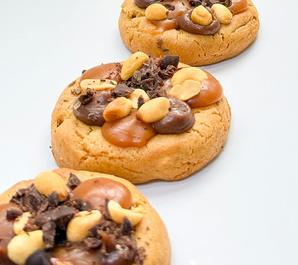 Three cookies with peanut butter, peanuts and chocolate on top