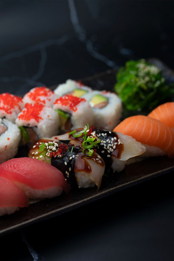 Food Photography of Close up up of delicious sushi with salmon, tuna, sesame seeds and glossy unagi sause.