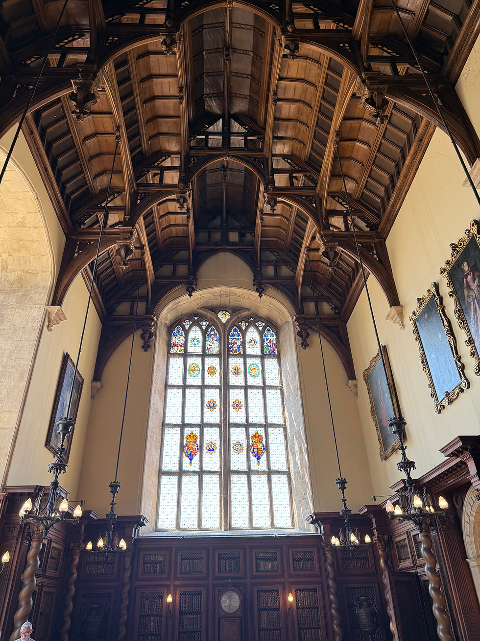 Tudor Great Hall at Burghley House, with its soaring hammer-beam timber roof and tall stained-glass window, a surviving interior from the house known by Anne Cecil in the sixteenth century.