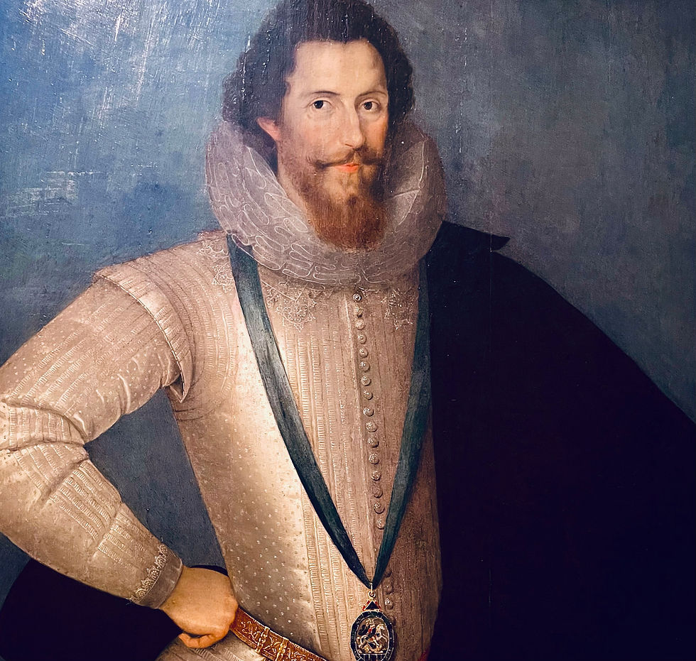 Formal Elizabethan portrait of Robert Devereux, 2nd Earl of Essex, shown three-quarter length in gleaming silver-white armor with a high lace ruff from the National Gallery of Art, Washington, DC. He wears the deep-blue ribbon and star of the Order of the Garter around his neck, a symbol of royal favor that foreshadows his dramatic fall. His face is confident, and slightly defiant — the queen’s handsome favorite who dared to turn his back on Elizabeth I and earned a legendary cuff to the ear.