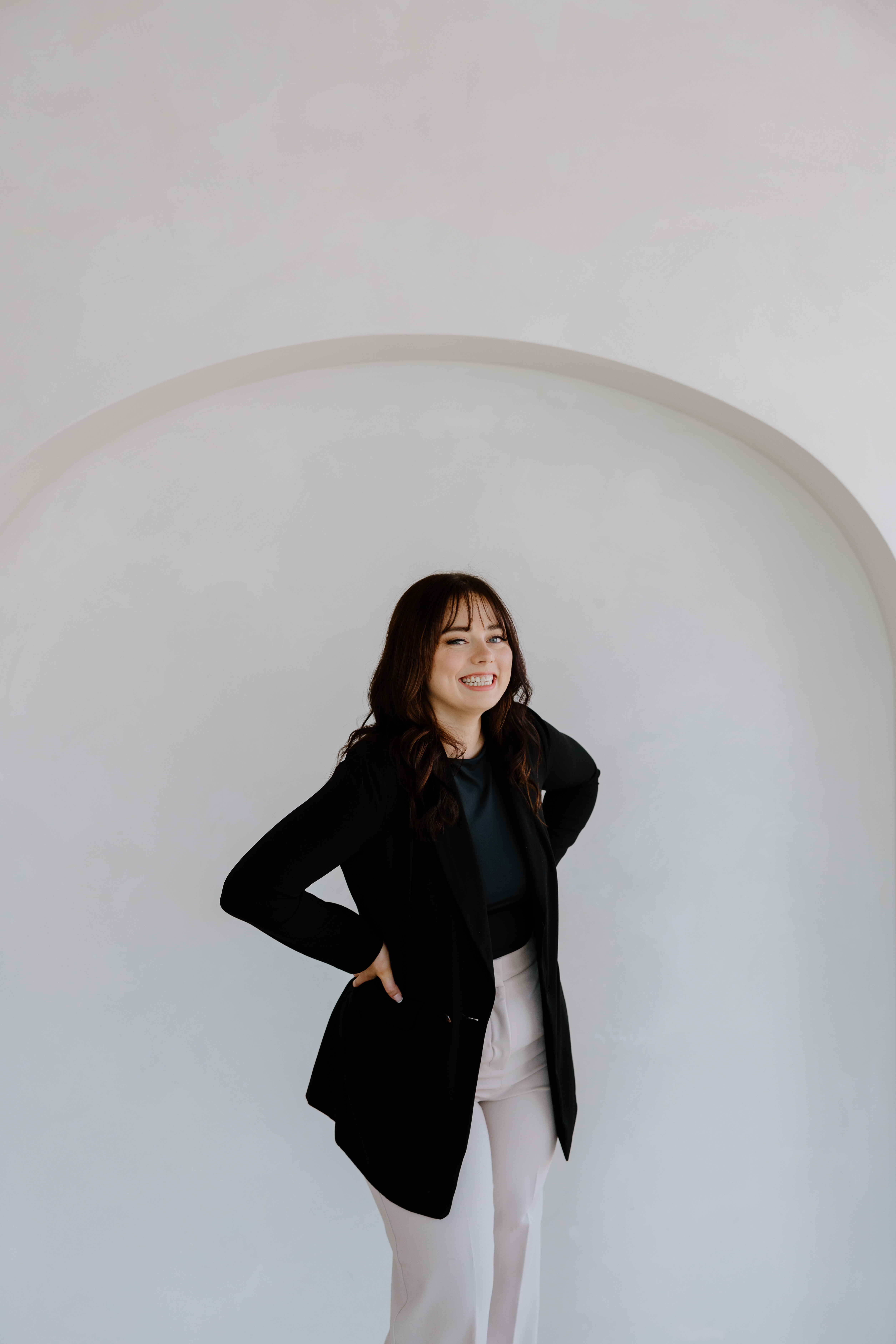 Paige, founder of Easy Peasy VA, smiling in a black blazer against a white arched wall