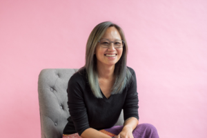 Sophie Khoo of Sophie Khoo Coaching smiling in glasses against a pink backdrop — Easy Peasy VA client
testimonial photo