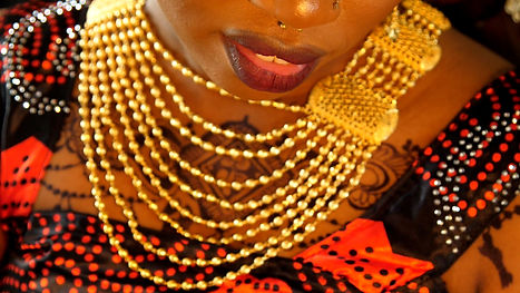 A woman in a gold necklace and black and red dress.