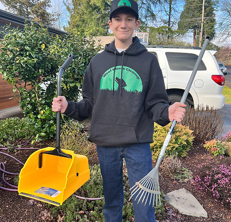 Samuel standing in full Woof Waste Cleanup gear, holding a waste scooper and bucket, ready for service in a residential yard.