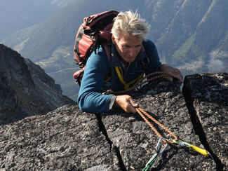 rock climber ascending a high boulder; represents the hanged man tarot card