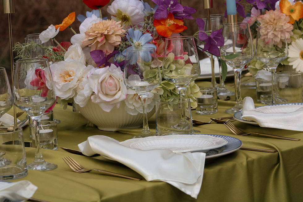 Outdoor wedding tablescape with tall candles, gold tableware and vibrant artificial floral centrepieces by Eventity.