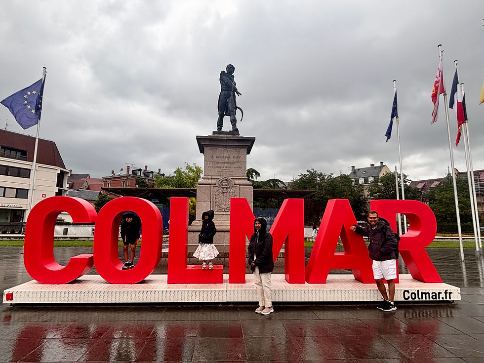 The colorful "COLMAR" sign in front of an old monument