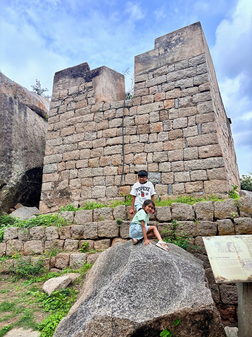 Children explore the historic stone wall, with a cannon point visible above.
