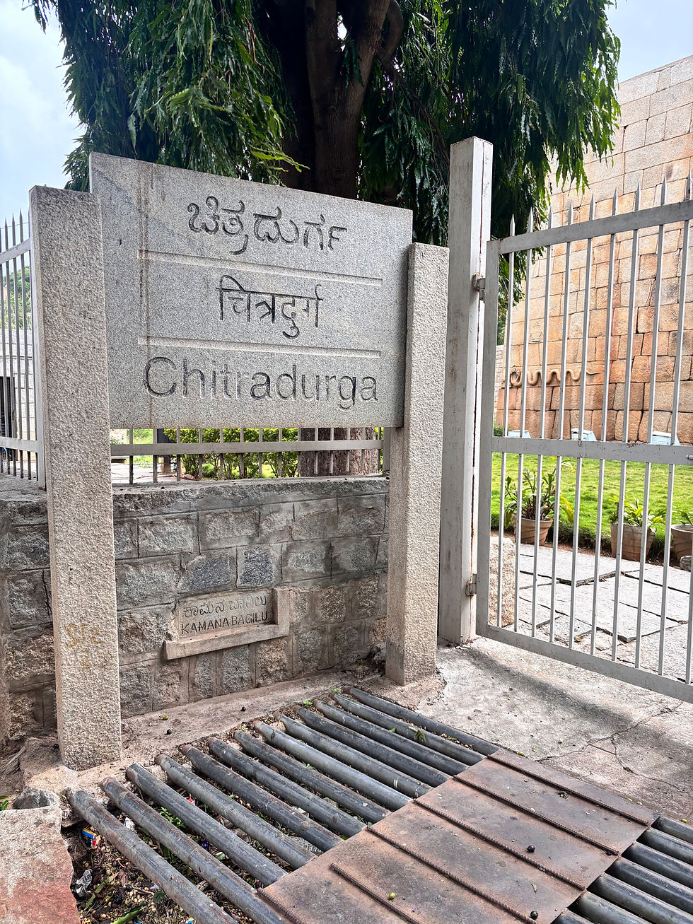 Entrance gate of the historic Chitradurga Fort, adorned with a welcoming sign in multiple languages.