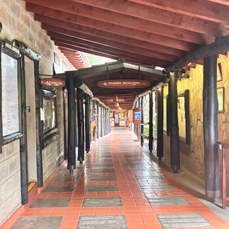The rustic hallway at Sarova Lion Hill, lined with wooden beams and tiled floors