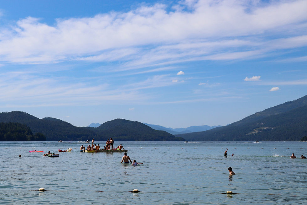 Family swimming and relaxing on Whitefish Lake with mountain views in Whitefish Montana