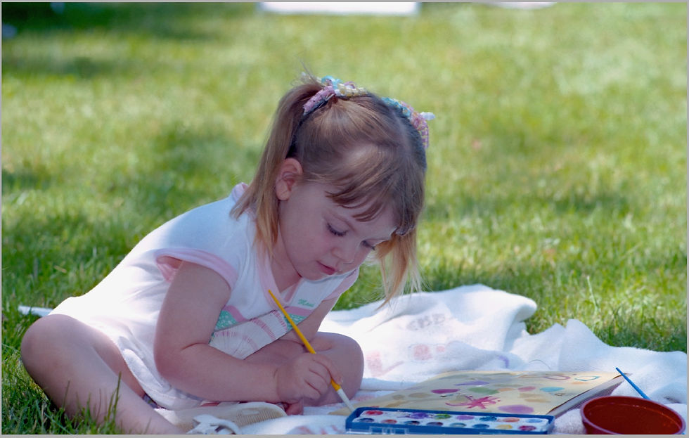 Throwback photo of owner of Painting With Sugar, Sarah Lamoureux at 4 years old painting with watercolors in the grass. Early 90's nostalgia