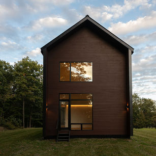 Big bedroom windows reflect trees in sunset.