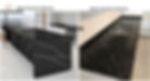 Side-by-side kitchen comparison showing black quartz with a smooth, consistent gloss finish on one countertop and black granite with natural veining and glossy texture on the other, highlighting the visual and stylistic differences between the two surfaces.