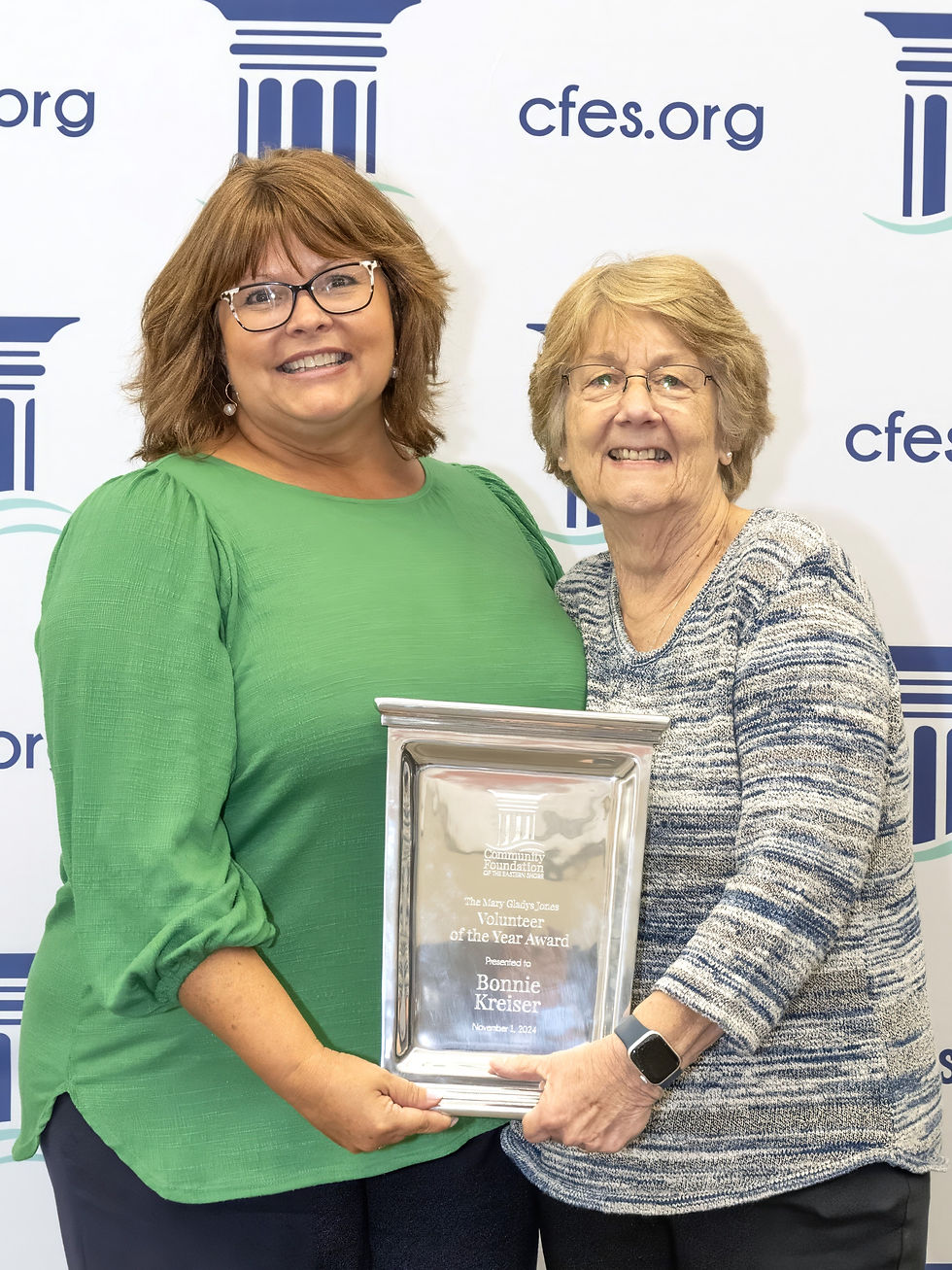 Two women hold up an award