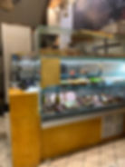 A deli counter with meats, sauces, and bowls of toppings displayed. 