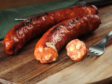 gegrillte Käsekrainer auf einem Holzbrett in stimmungsvollem Licht mit Beilage und Dekorat