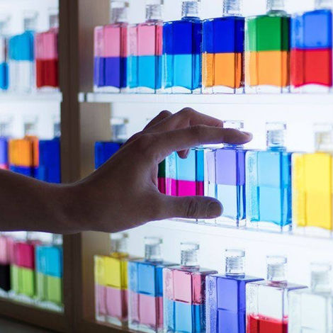 A hand selecting an Aura-Soma colour therapy bottle, used in personal coaching and energy alignment sessions at Art & Soul