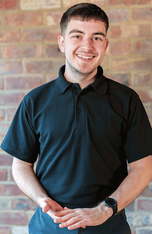 Smiling man in black polo shirt against brick wall