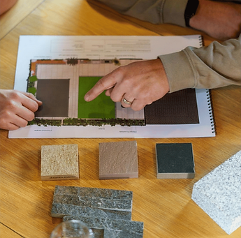 Person pointing at landscape design plan with material samples.