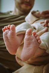 Close-up of newborn baby’s tiny feet held by mother’s hands during an at-home photoshoot in Calgary