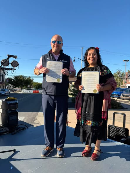 Mayor Kamron Yates and committee member Nora Hernandez, holding the proclamation in English and Spanish.