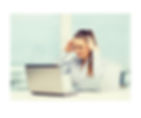 Woman sitting at a computer holding her head in her hands frustrated by miscommunication