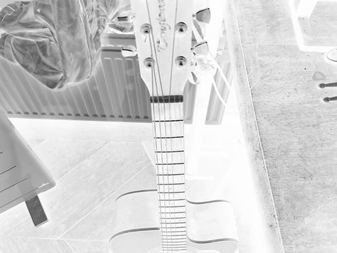 Acoustic guitar headstock and body shown in an artistic inverted color negative effect.