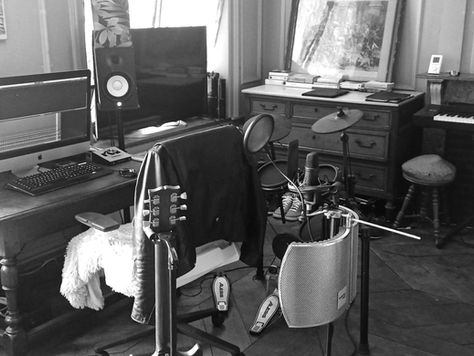 Home studio setup with a computer, electric drums, and guitars.