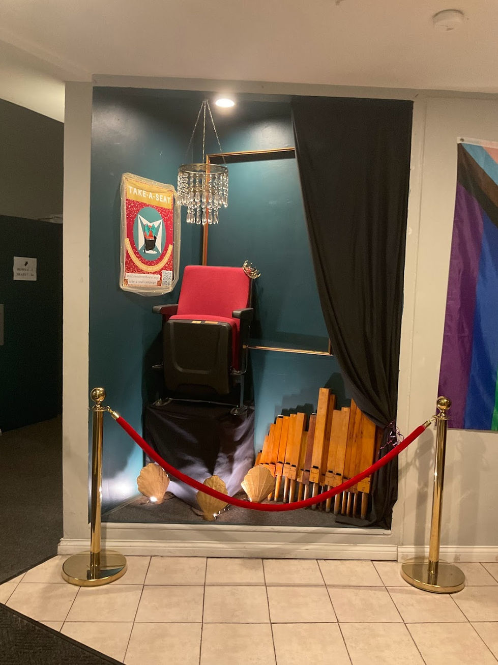 The Take-A-Seat Plaque fundraiser display at the front of Madison Street Theater decorated with organ pipes, shell shaped uplighting, and a chandelier for "The Revolutionists"
