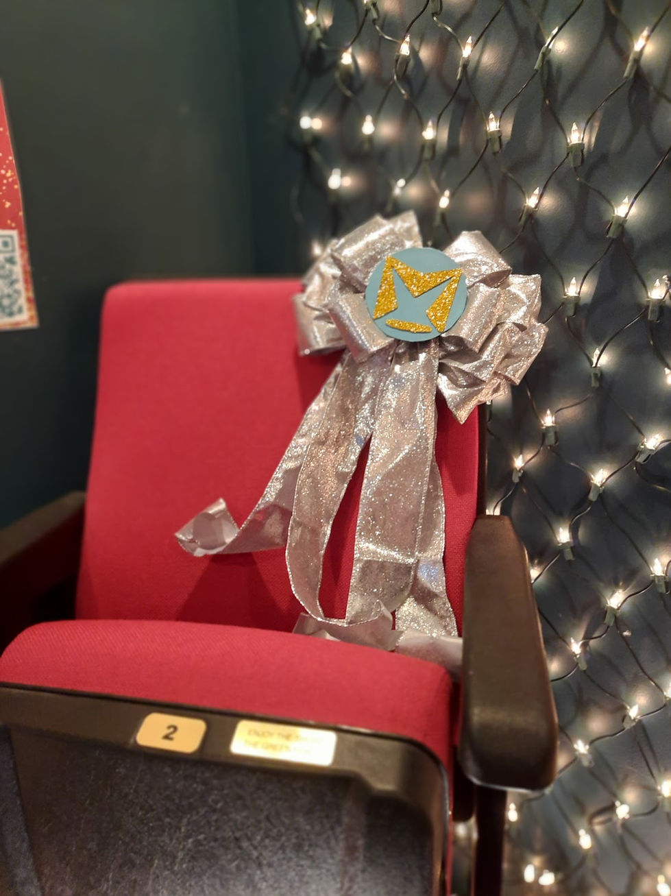 MST logo in the center of a silver bow decorating a red theater seat