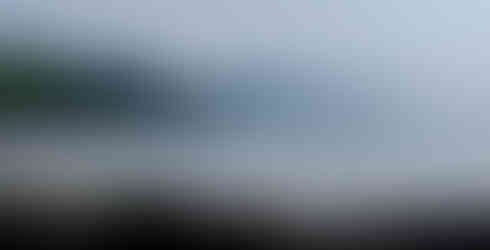 Lone surfer carrying a board on a sandy empty beach with mountains in the background. Surfing in the Atlantic with stunning scenery.