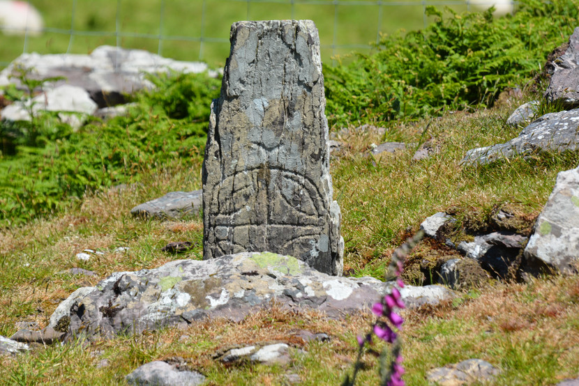 small standing stone with old carved cross, standing in a field