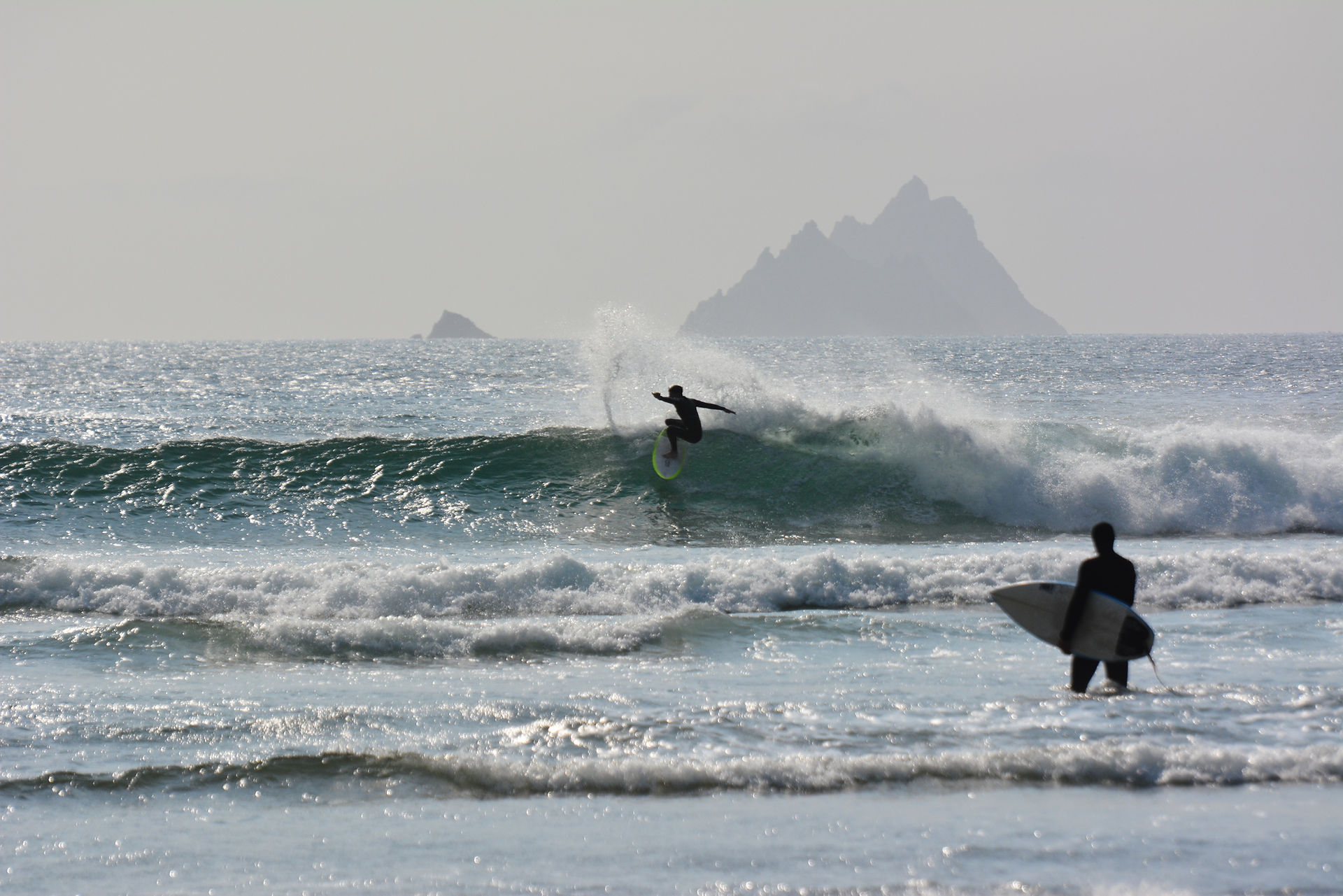2  surfers in the Atlantic ocean with the Skellig Islands in the distance