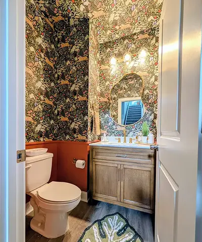 Floral wallpaper bathroom with wood vanity and round mirror – Pinehurst, NC handyman project