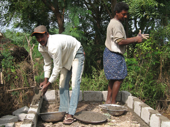 Mason building the walls of a latrine