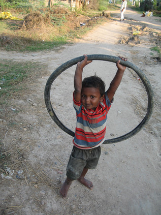 Young boy holds up a bike tire (his toy) in Ganapavaram