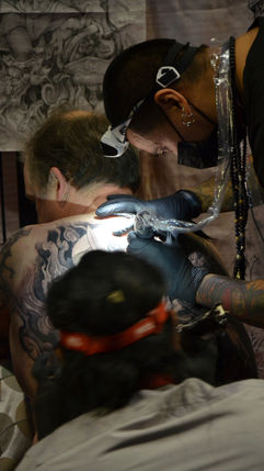 Tattoo artist creating a detailed design on a client’s skin