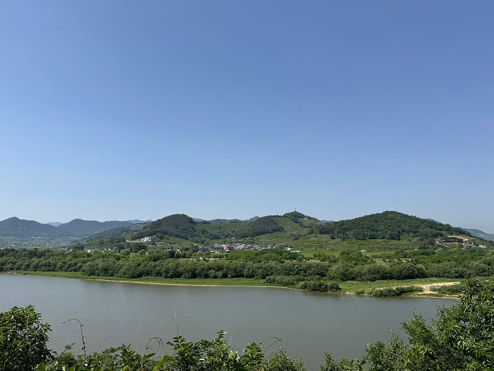 Tranquil riverside view with lush green hills under a clear blue sky.