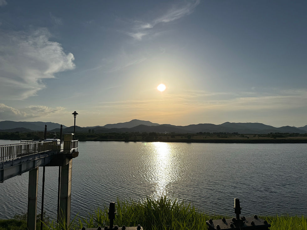 Sunset over a serene lake with distant mountains.