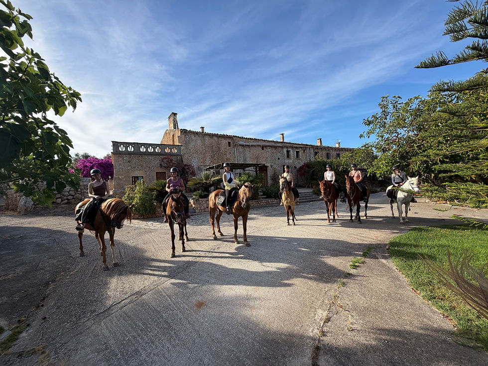 Eine Gruppe Reiter auf ihren Pferden vor historischer Finca in schöner Natur in Mallorca.