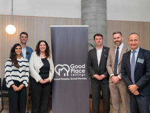 Board and team members of Good Place Lettings smiling beside a Good Place Lettings display sign