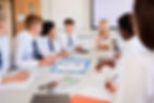 Female High School Teacher Sitting At Table With Teenage Pupils Wearing Uniform Teaching L