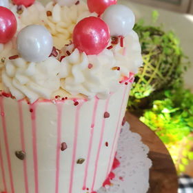 pink and white single tier cake with large sprinkle accents